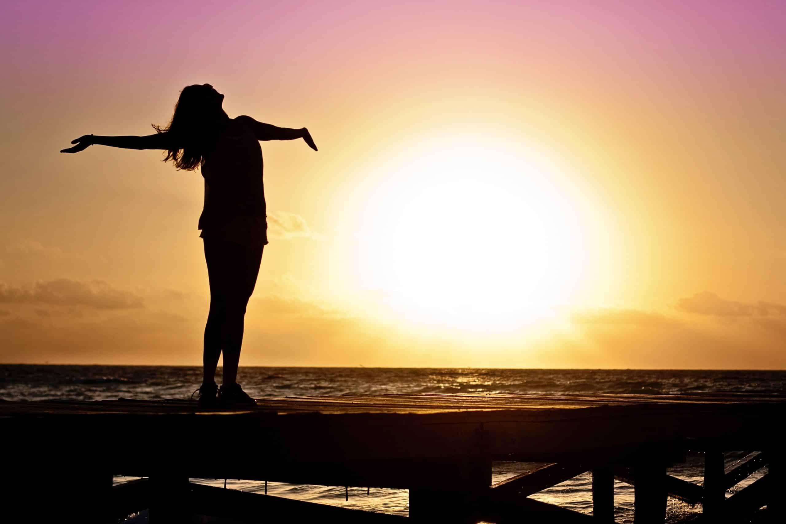 Person with long hair by the beach during sunset enjoying freedom